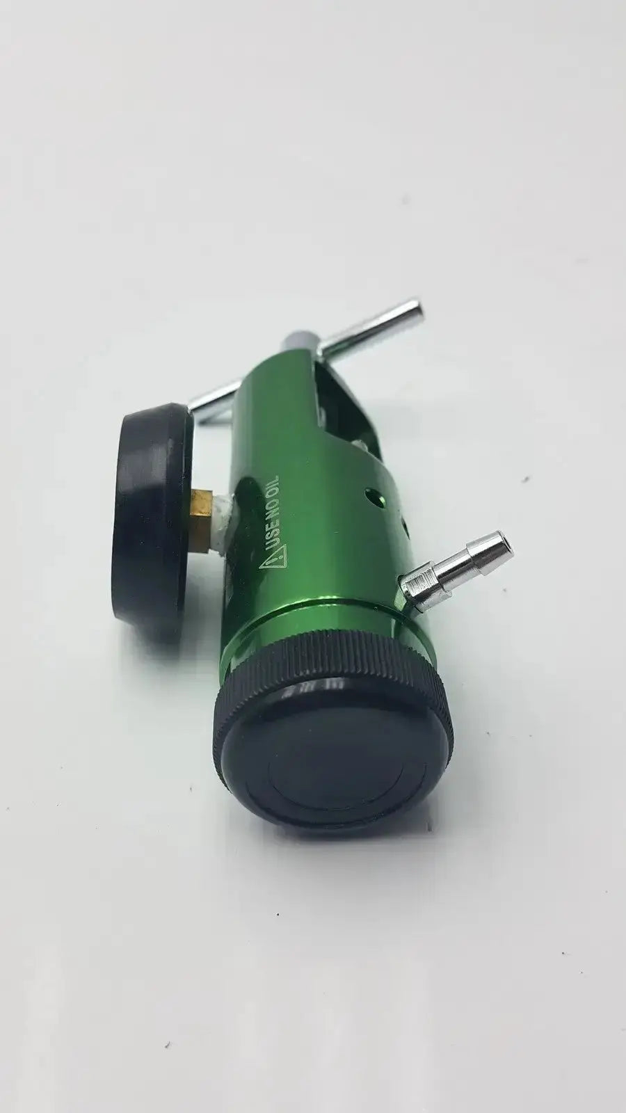 Green metal medical oxygen regulator with black knobs and silver fittings for controlling medical oxygen flow