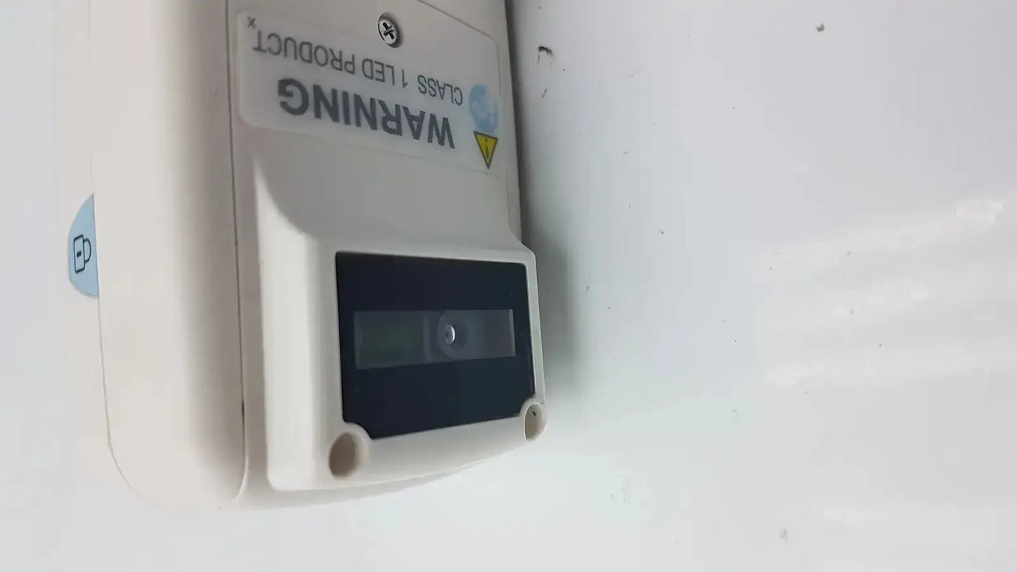 White plastic led light fixture with black rectangular panel and warning label on the back of drager jaundice meter jm-105