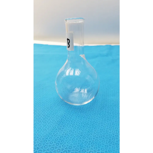 Clear glass round-bottom flask with a narrow neck and a white label marked ’b’ on its side.