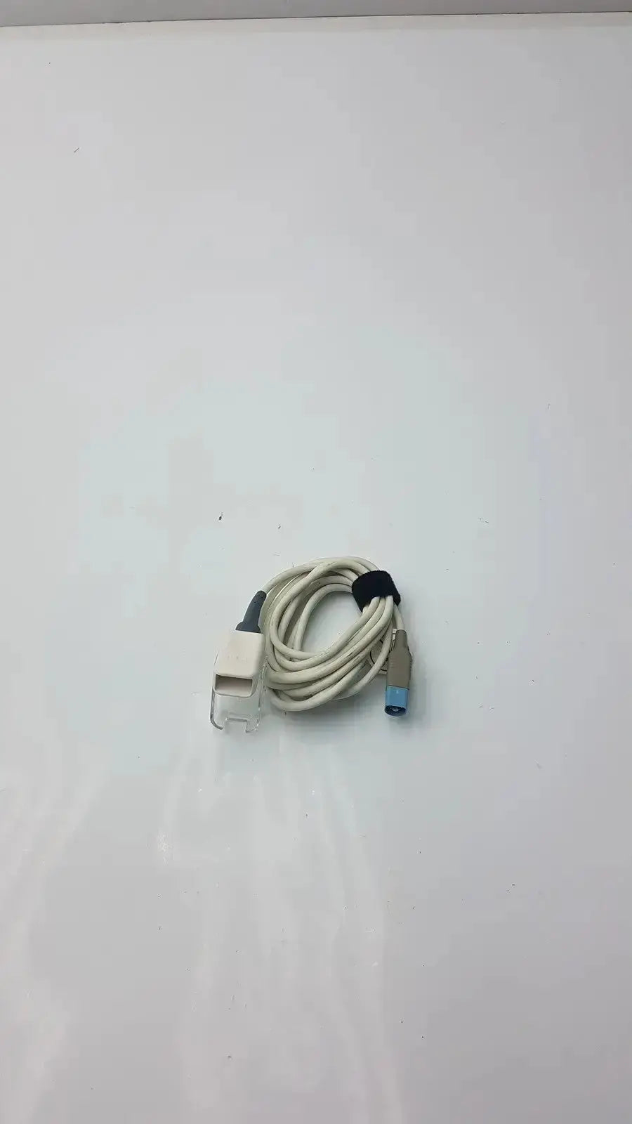 Beige coiled masimo ps-10153d cable interface with clear plastic and blue 8-pin to 9-pin plugs secured by black zip tie
