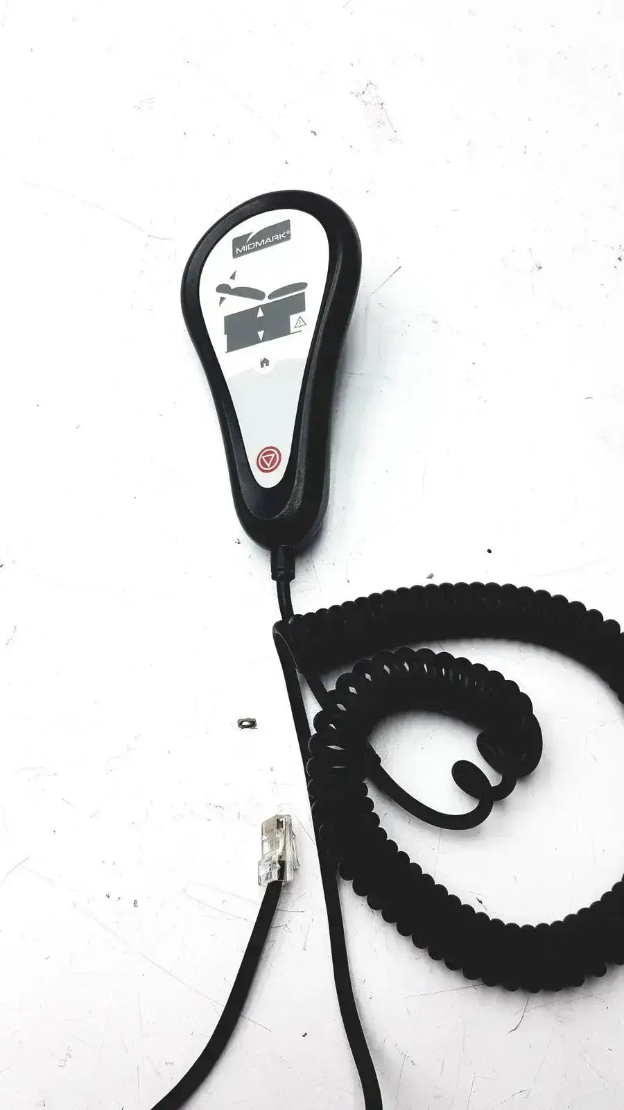 Black coiled cable connected to a black and white midmark exam table hand remote control with brand name visible