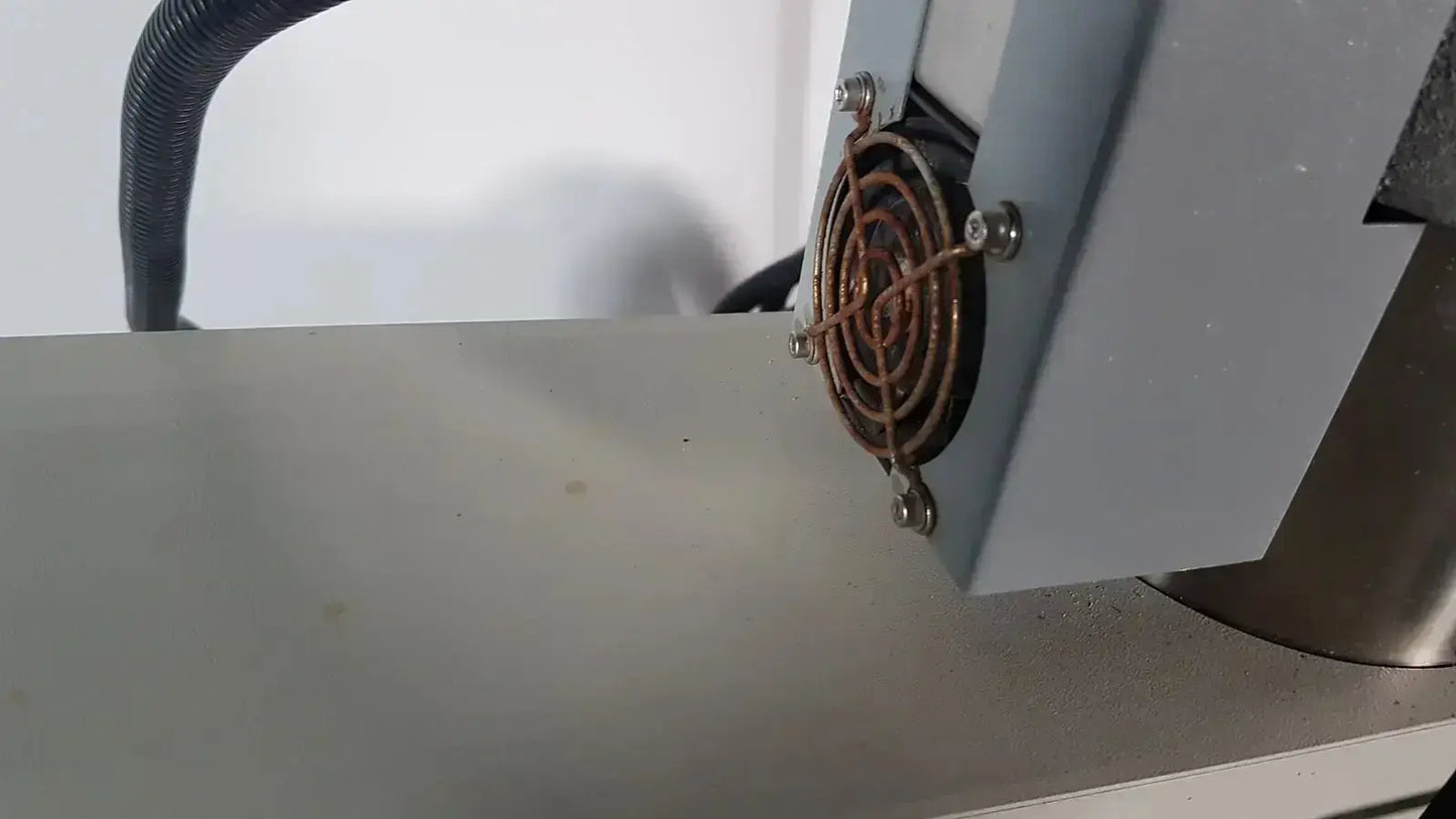 A copper cooling fan with metal mesh grille secured by four screws on the gray Netzsch GmbH simultaneous thermal analyzer