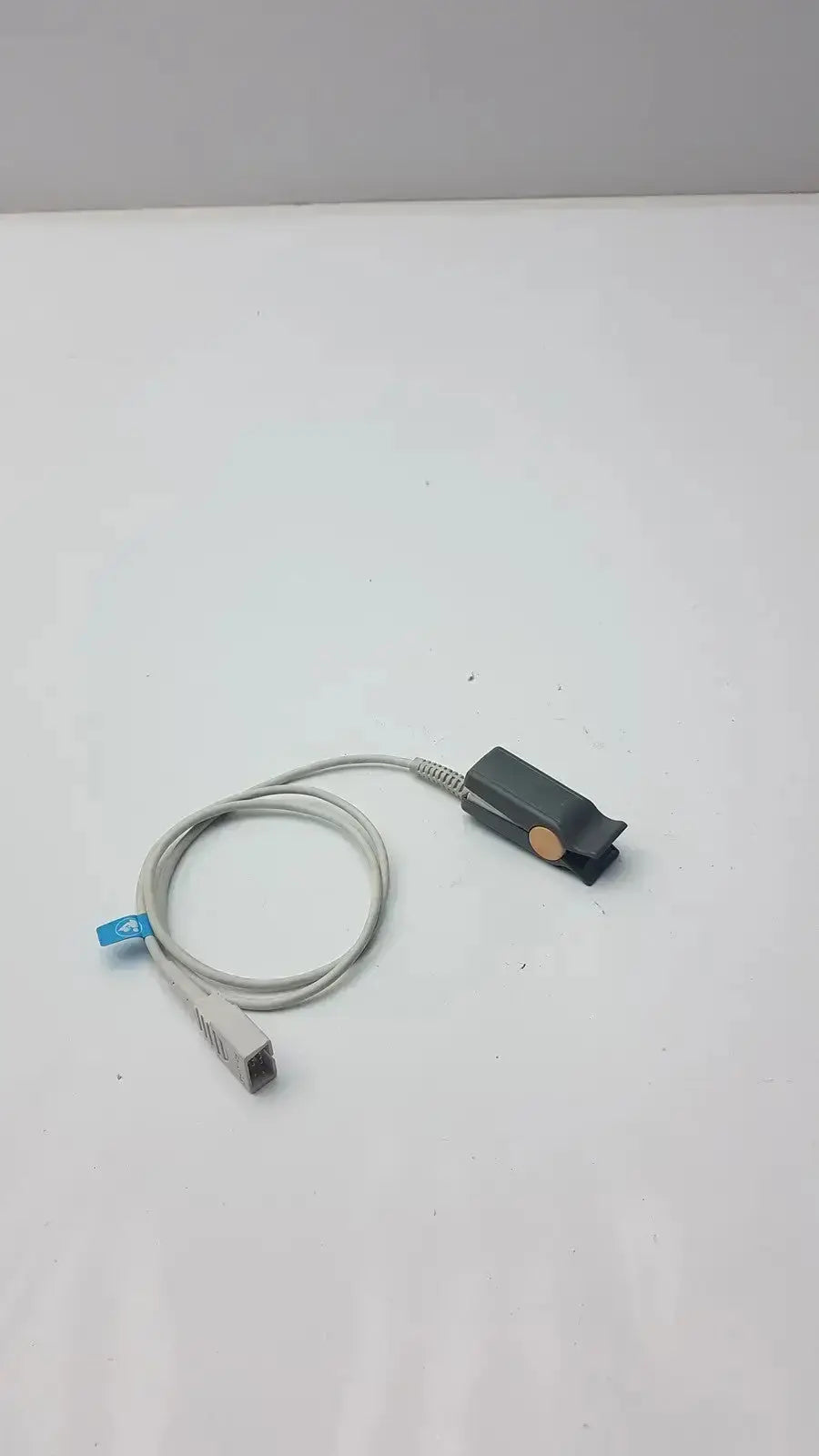 Philips m1196t reusable gray pulse oximeter with coiled cable and small blue tag near the sensor connector