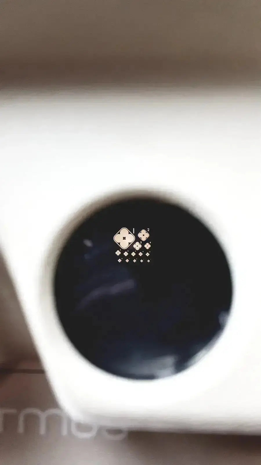 White ceramic cup with dark liquid and gold logo rim featured in titmus optical ii vision tester product