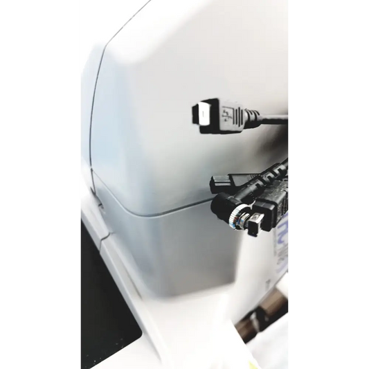 White plastic device with multiple black cables plugged into its side ports.