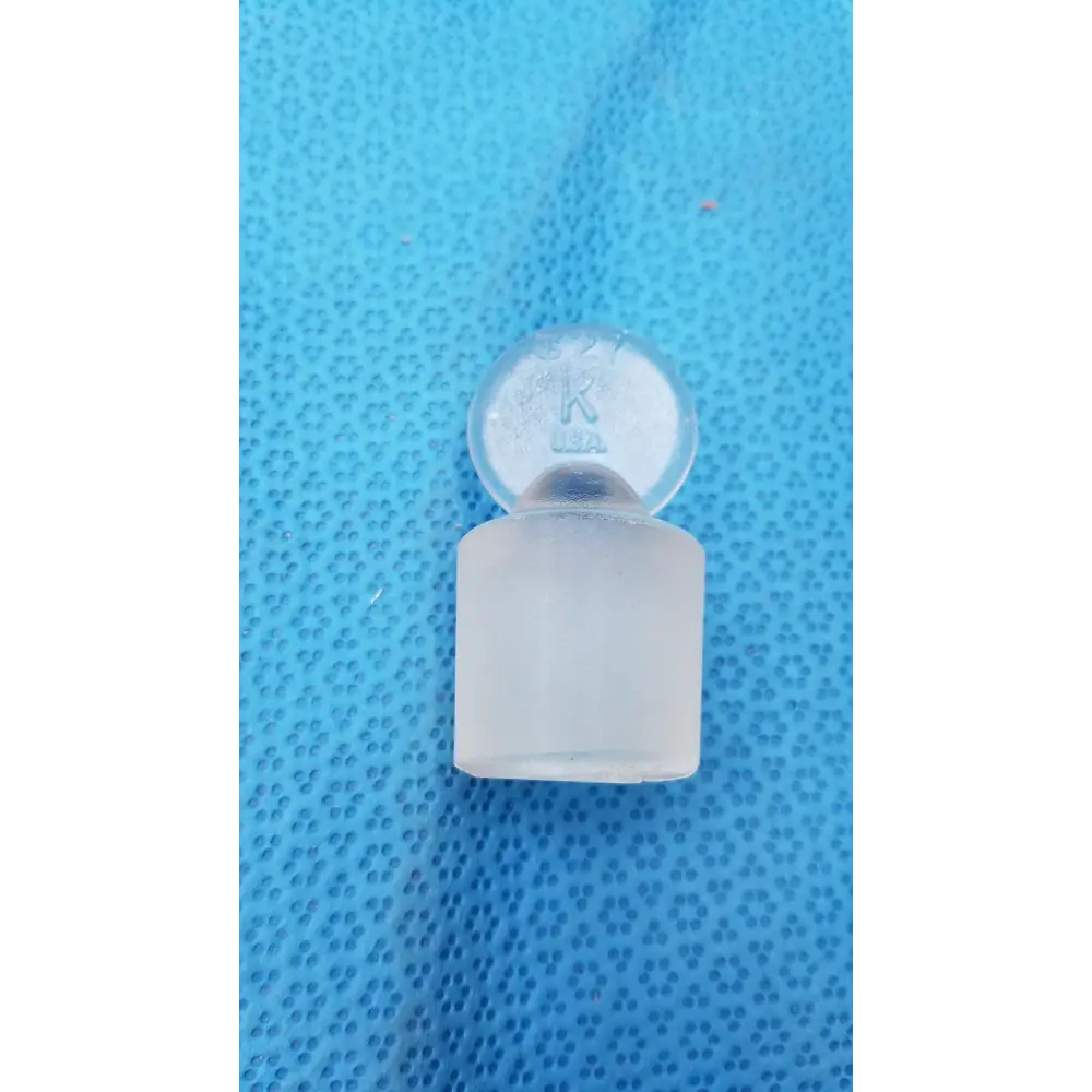 Clear glass laboratory stopper with a frosted cylindrical base and a rounded top featuring engraved markings.