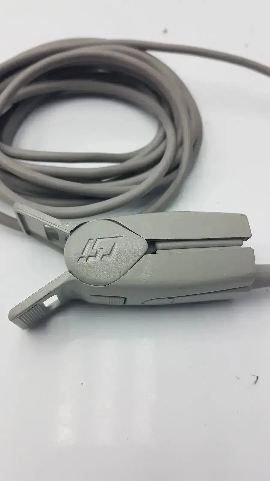Gray plastic 6-pin spo2 finger clip with coiled gray finger clip cable and embossed logo on clamping mechanism