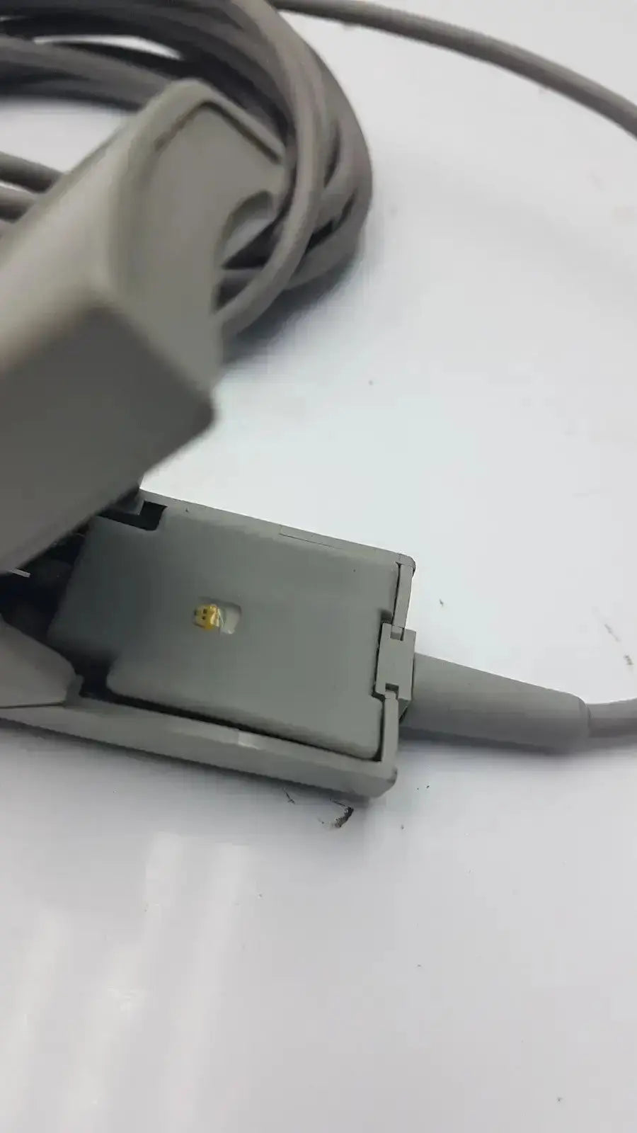 Gray plastic 6-pin spo2 finger clip cable with coiled cord and gold-colored adult finger clip sensor for pulse oximetry