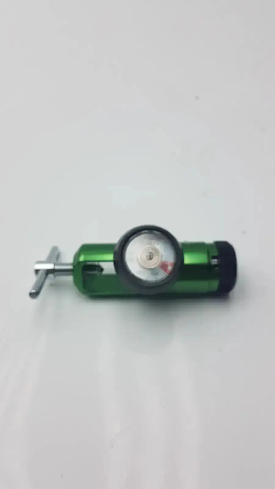 Access Point medical oxygen regulator showing green body with black pressure gauge and silver adjustment knob