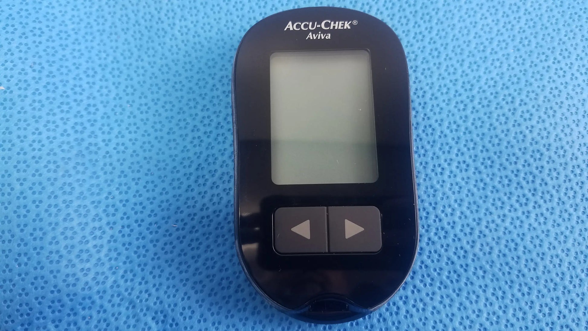 Black Accu Chek Aviva blood glucose meter with rectangular screen and two buttons in medical equipment kit with bag