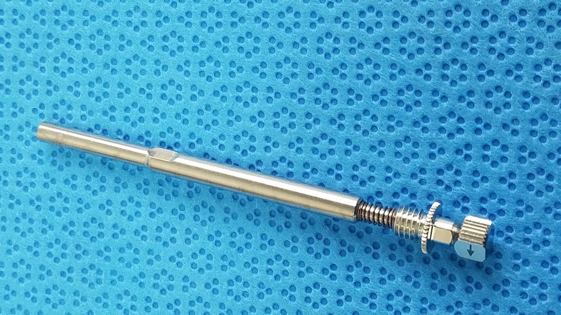 Silver-colored metal screw with threaded shaft and knurled knob in ace 765-1001 sterilization tray for dental implant equipment