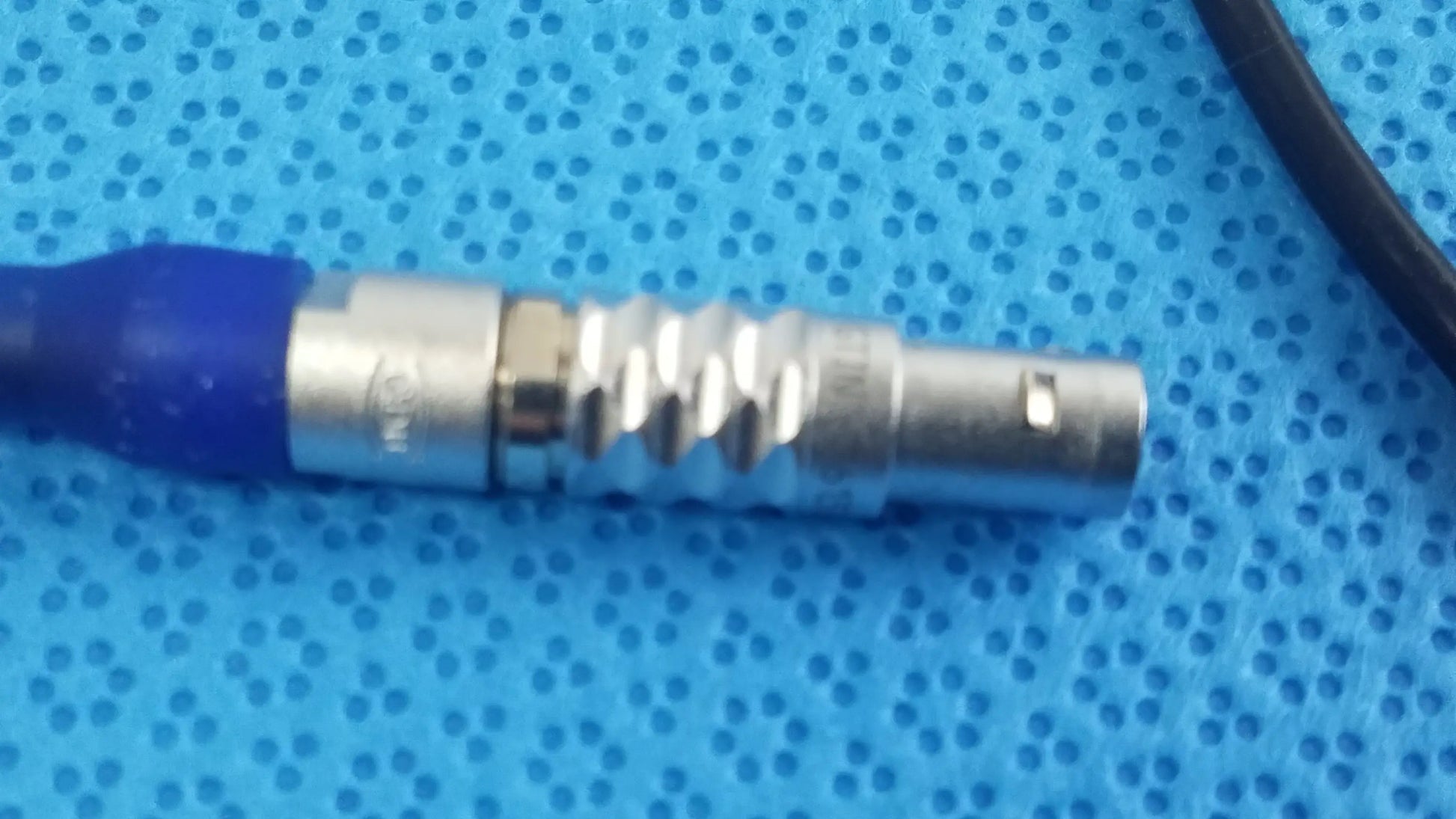 Silver-colored metal connector with blue rubber boot and ridged texture in ace 765-1002 sterilization tray for multigen radiofrequency probe