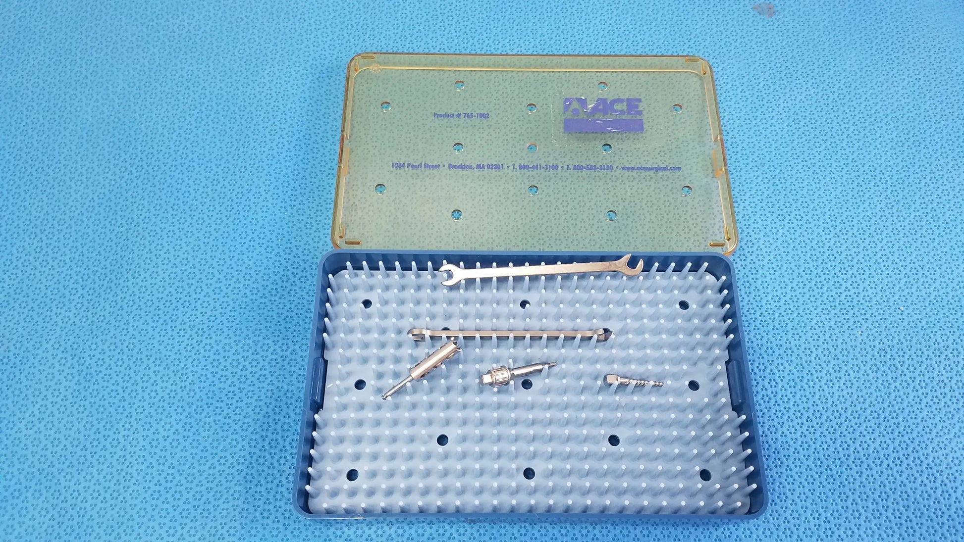 Blue plastic surgical instrument case with translucent green lid containing metallic tools for reuse medical equipment