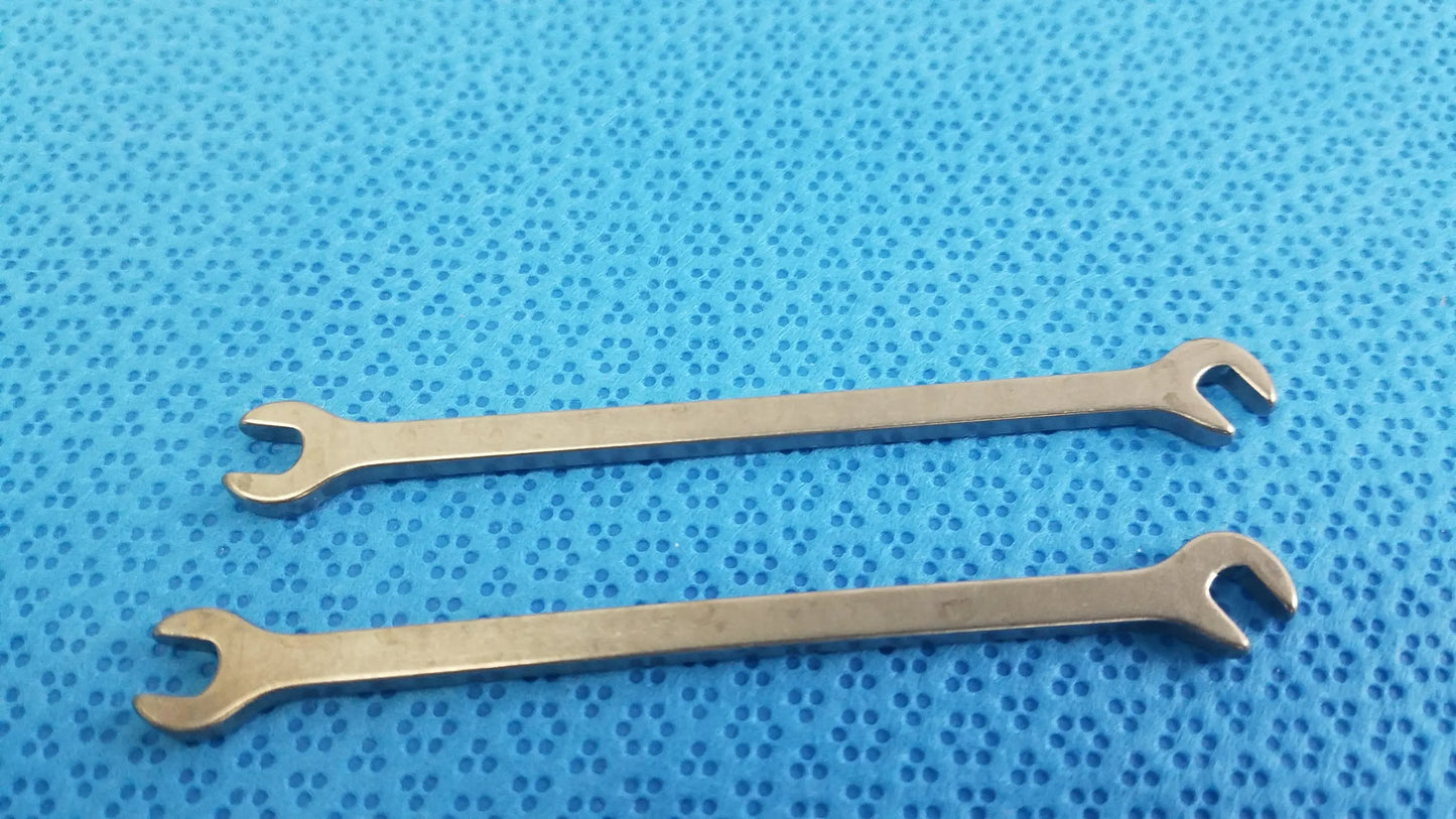 Two polished silver metallic open-end wrenches from ace ophthalmology micro surgery medical equipment on blue surface