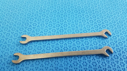 Two polished silver metallic open-end wrenches from ace ophthalmology micro surgery medical equipment on blue surface