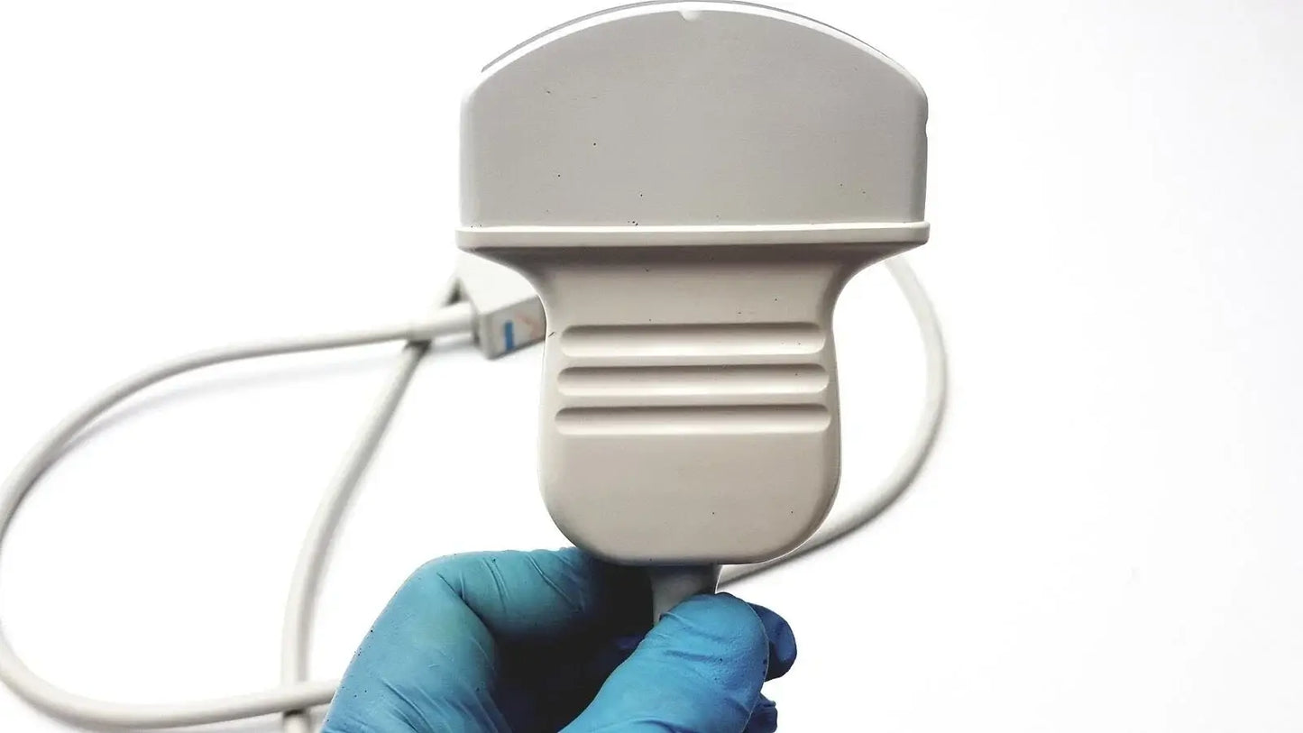 Gray plastic acuson c3 needle guide convex ultrasound transducer probe with ribbed grip held by gloved hand medical equipment