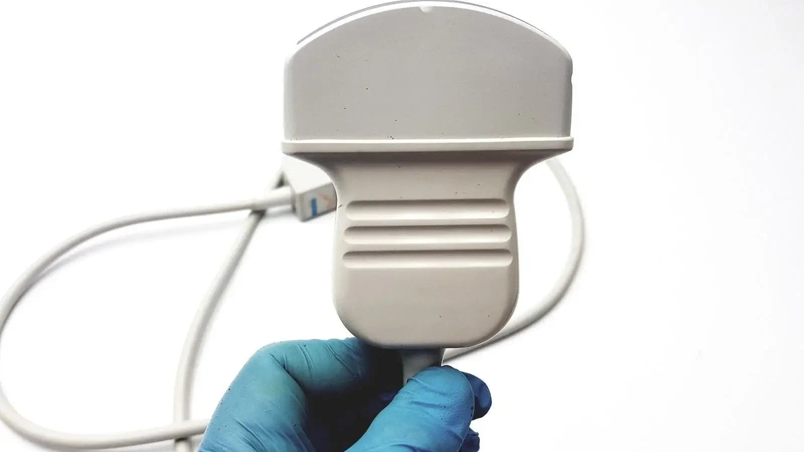 Gray plastic acuson c3 needle guide convex ultrasound transducer probe with ribbed grip held by gloved hand medical equipment