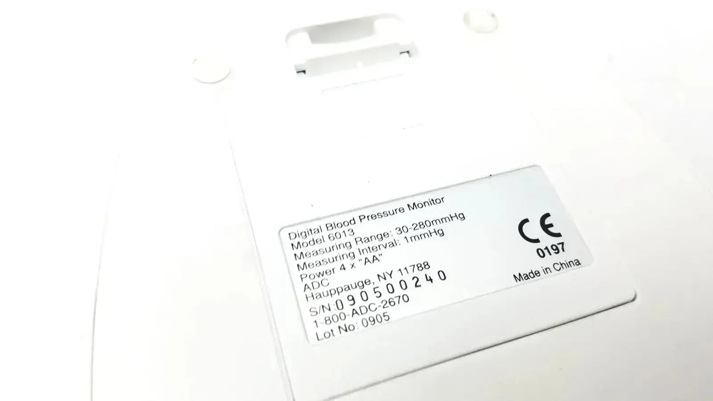 White plastic digital blood pressure monitor adc advantage 6013 series with model number and specifications label visible