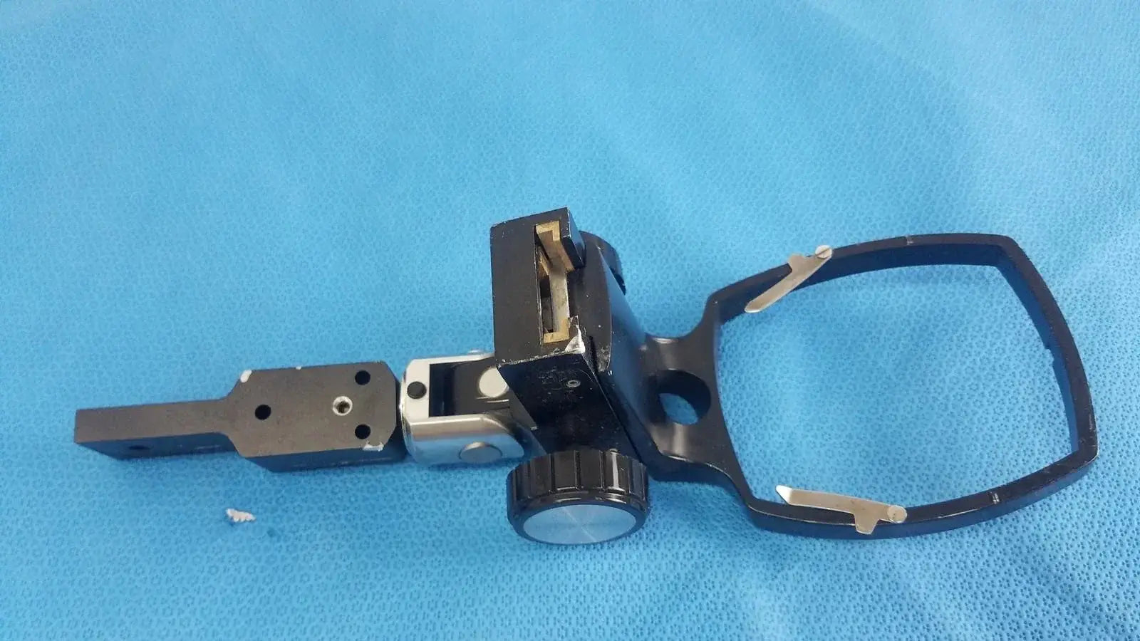 Black metal adjustable flash gun bracket with circular knob and rectangular mounting plate for reuse medical equipment