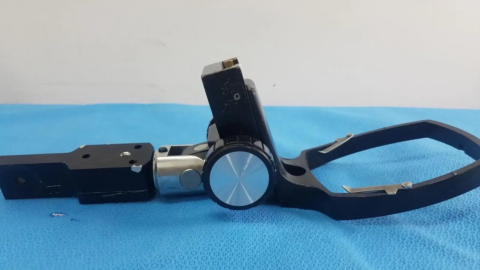 Adjustable flash gun bracket in black and silver with circular knob for secure clamp reuse medical equipment use