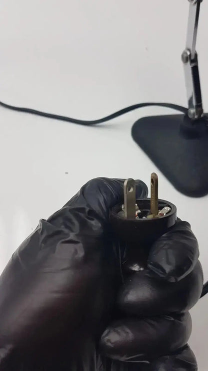Black rubberized plug with two brass-colored prongs for adjustable microscope illuminator light lamp back side view