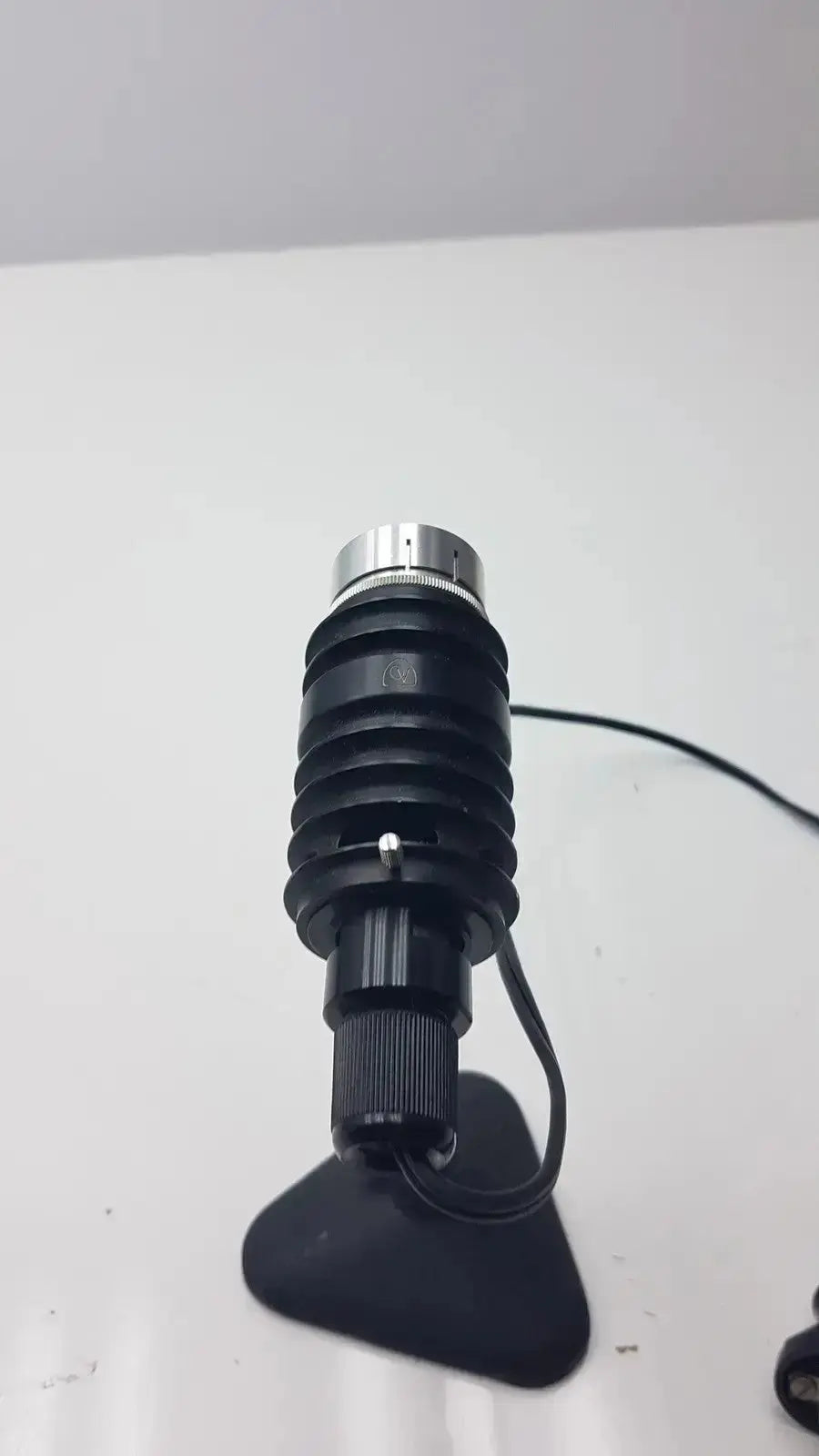 Black and silver adjustable microscope illuminator with ribbed body mounted on black triangular base for enhanced lighting