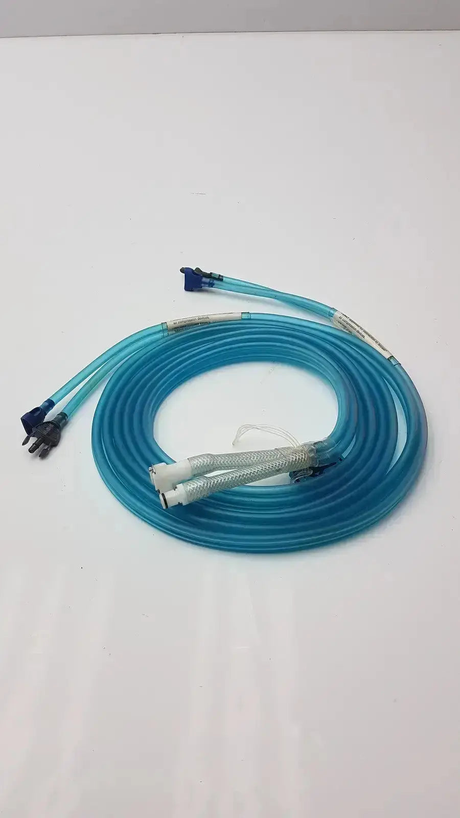A coiled translucent blue aiircast air comprressor hose with multiple connectors and a textured white section for compression devices