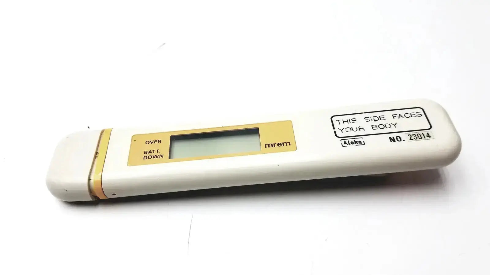 White and gold aloka pdm-253 mydose mini dosimeter with rectangular lcd screen displaying mrem for radiation measurement