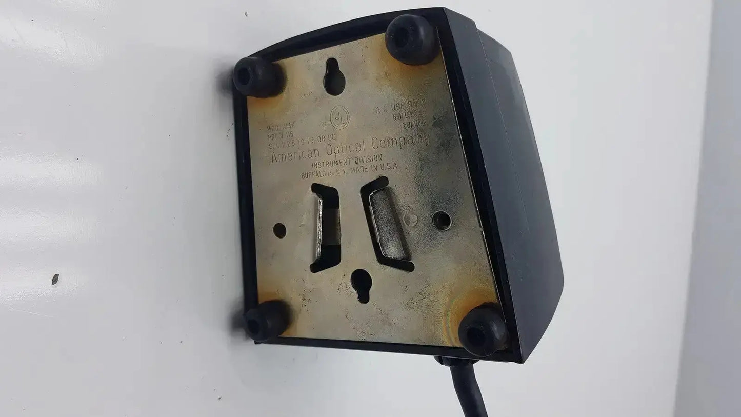 Black plastic wall-mounted american optical voltage selector pri 115v with brass engraved backplate and two rectangular slots