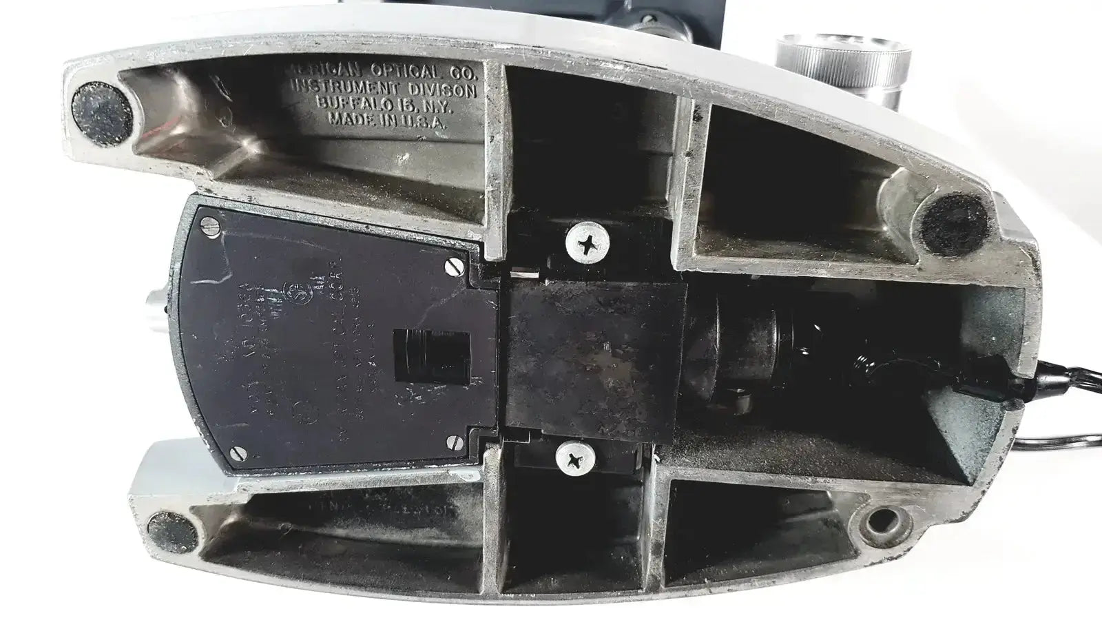 Silver metallic housing with black plastic components and engraved american optical co text on american optical spencer microscope