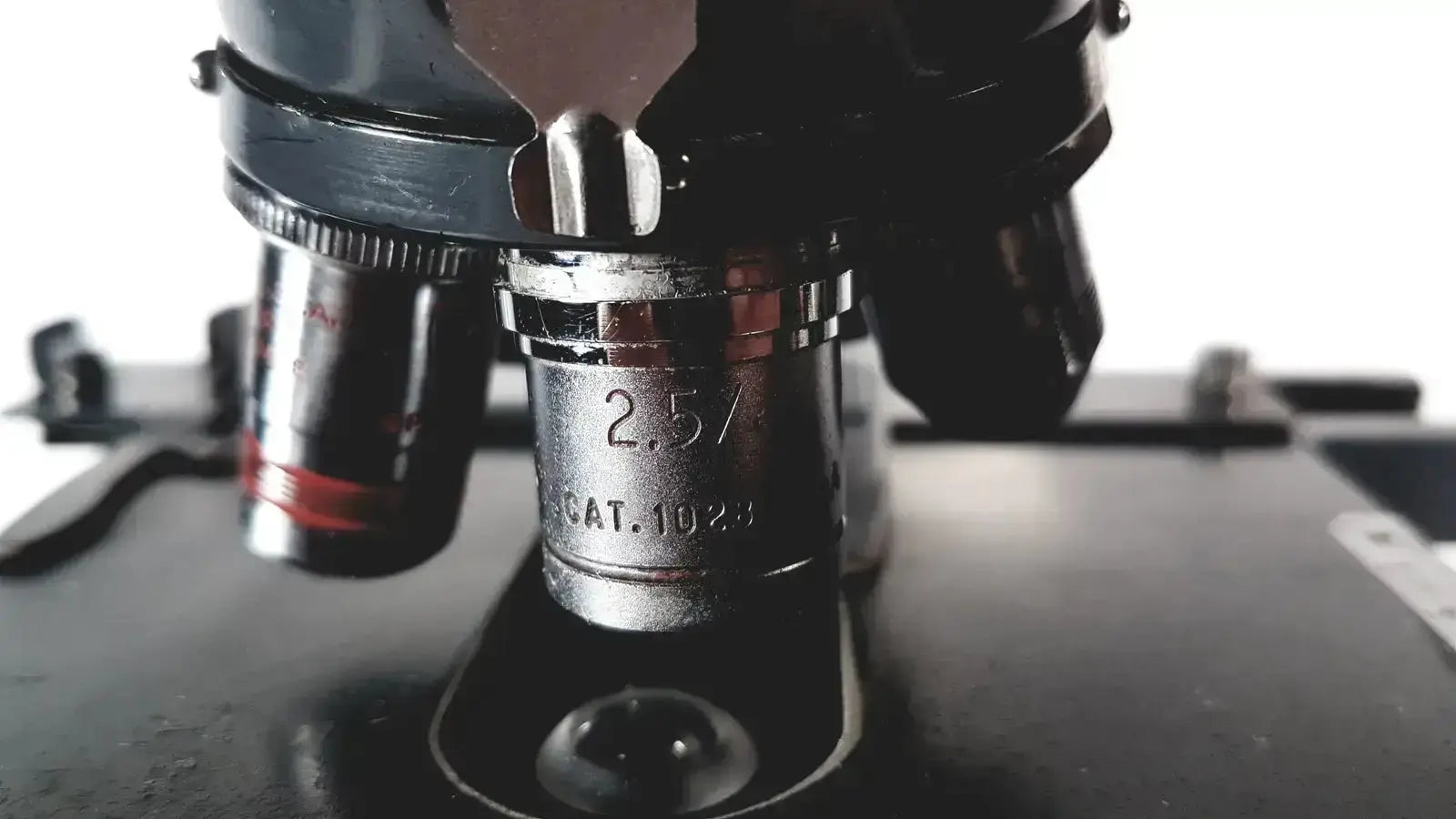 Black and silver microscope objective lens with engraved 2.5 catalog number on american optical spencer optical spencer microscope