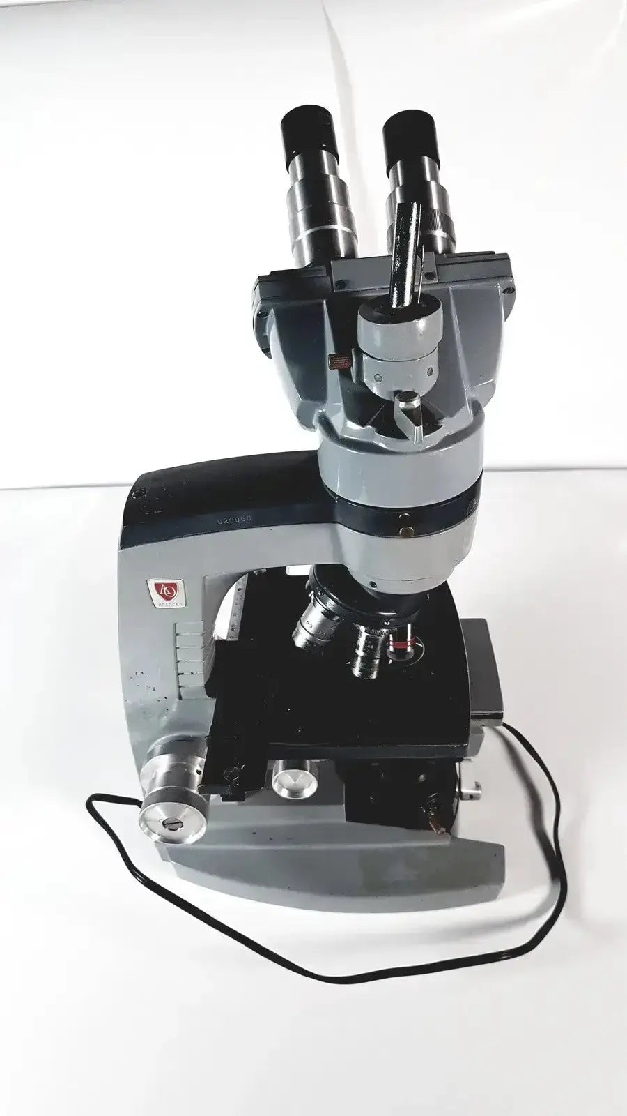 Silver and black american optical spencer microscope with dual eyepieces and adjustable focus knobs for specimen viewing