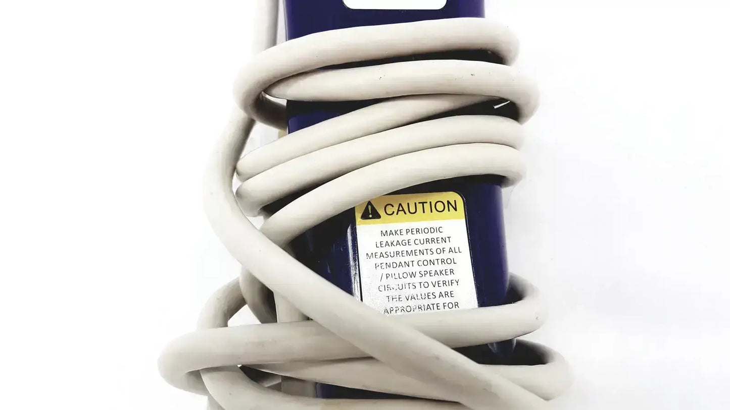 Coiled beige power cord wrapped around dark blue product box with yellow caution label for anacom medtek b0857-088dj nurse unit