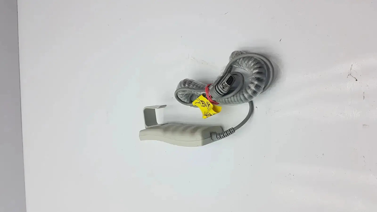 Gray coiled cable with beige handheld grip and yellow warning tags for arjo huntleigh patient lift remote handset