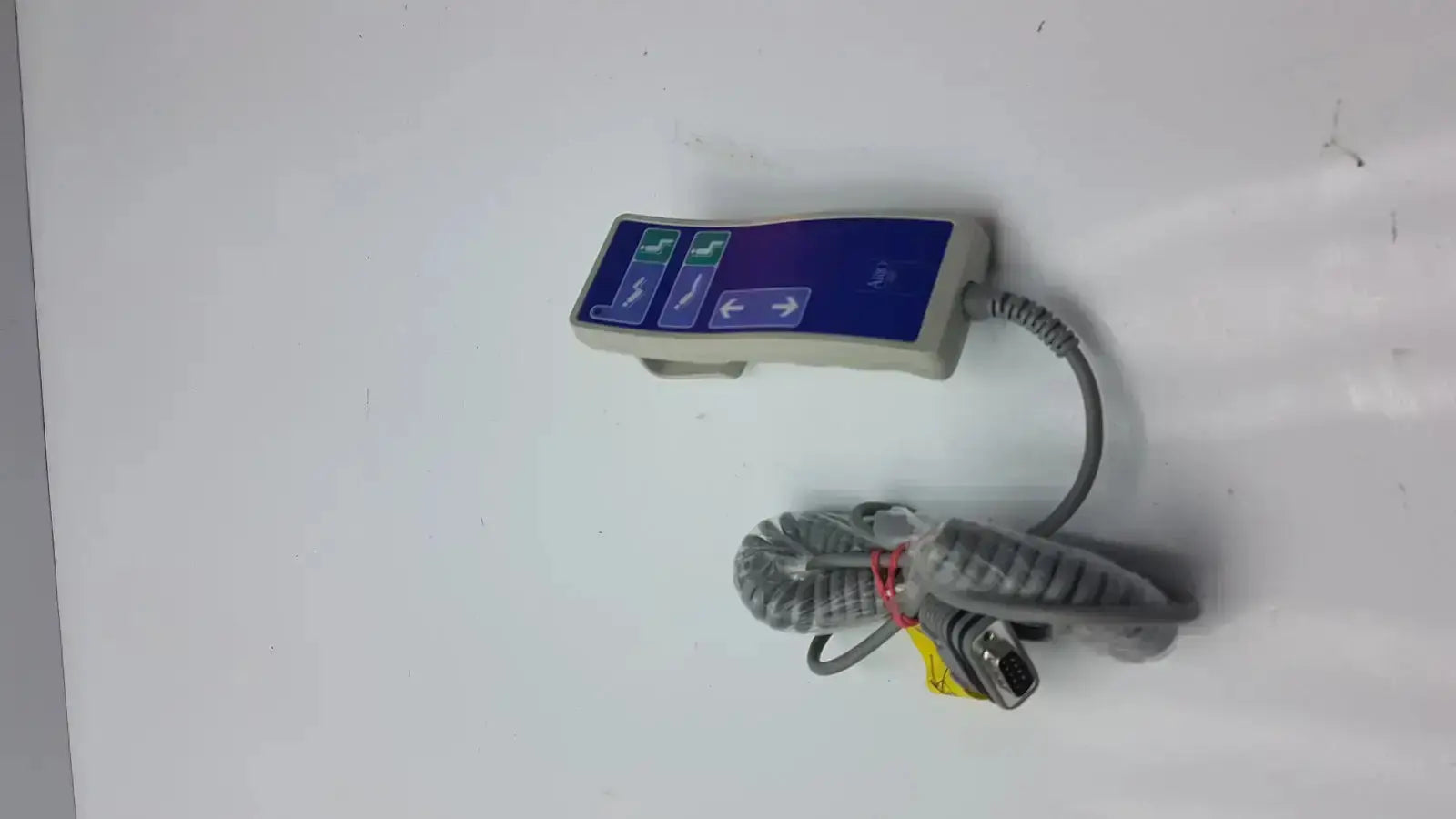 Gray Arjo Huntleigh patient lift remote handheld device with blue control panel and coiled cable with d-sub connector