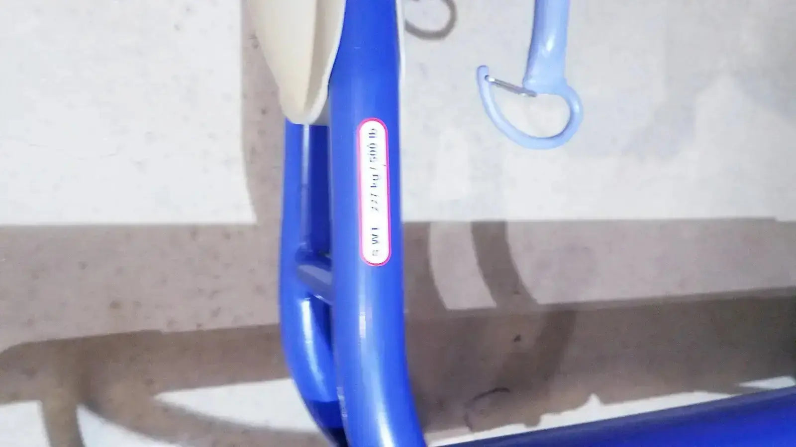 Blue plastic hook with white weight label on arjo maxi power patient lift for safe lifting support