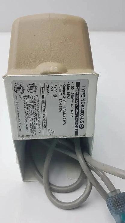 Beige plastic arjo type nda4000-us charger 100-240v with gray cables and input 24v dc 1a output label visible