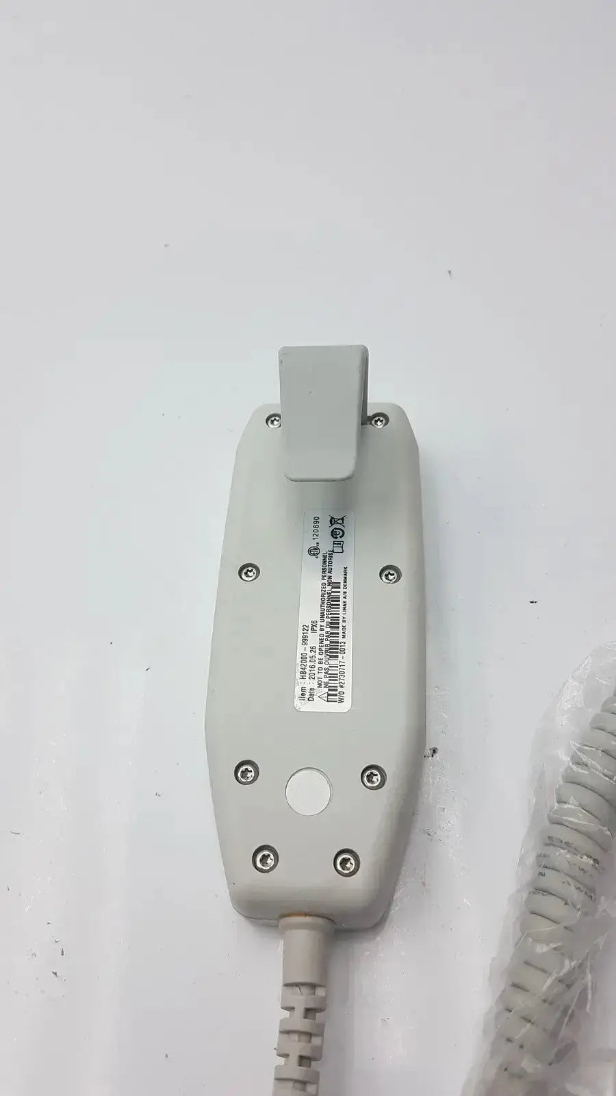 Gray plastic handheld atlas hb42000-999122 handset with coiled cable and small rectangular label shown from the back side