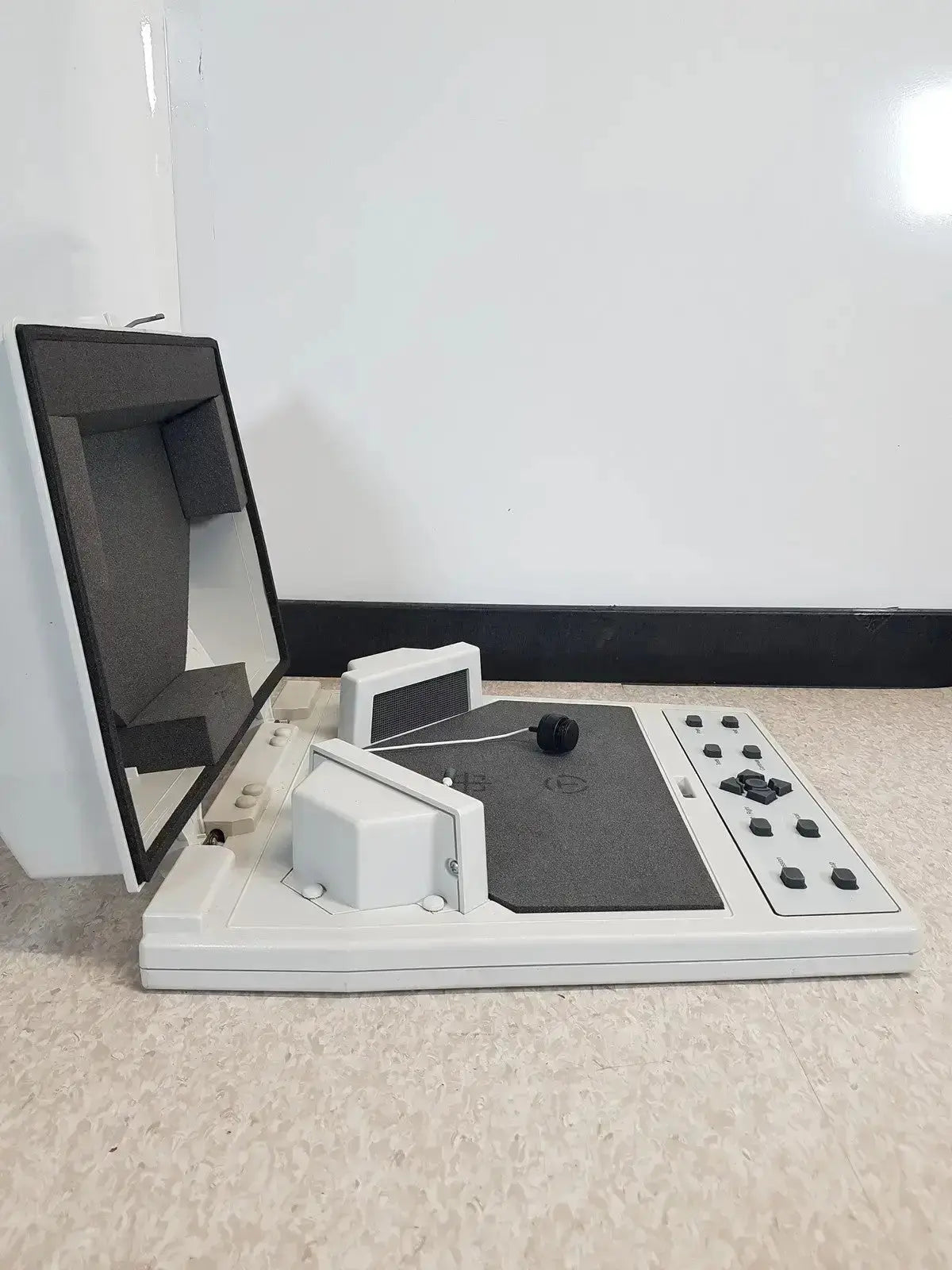 White and gray audioscan verifit vf-1 hearing aid analyzer with black screen and control panel on flat surface