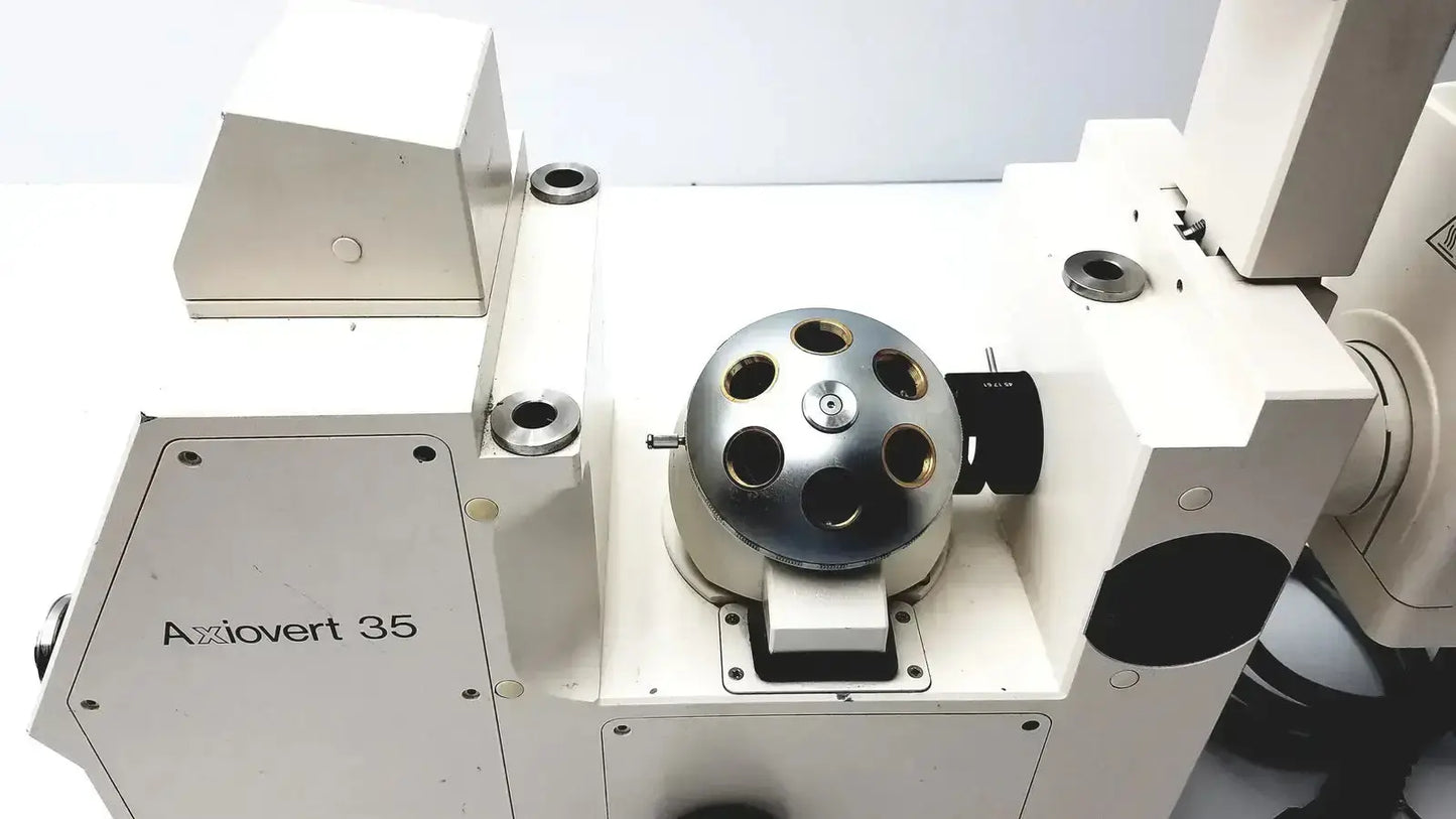 Silver metallic spherical component with circular apertures mounted on white axiovet 35 inverted phase contrast microscope