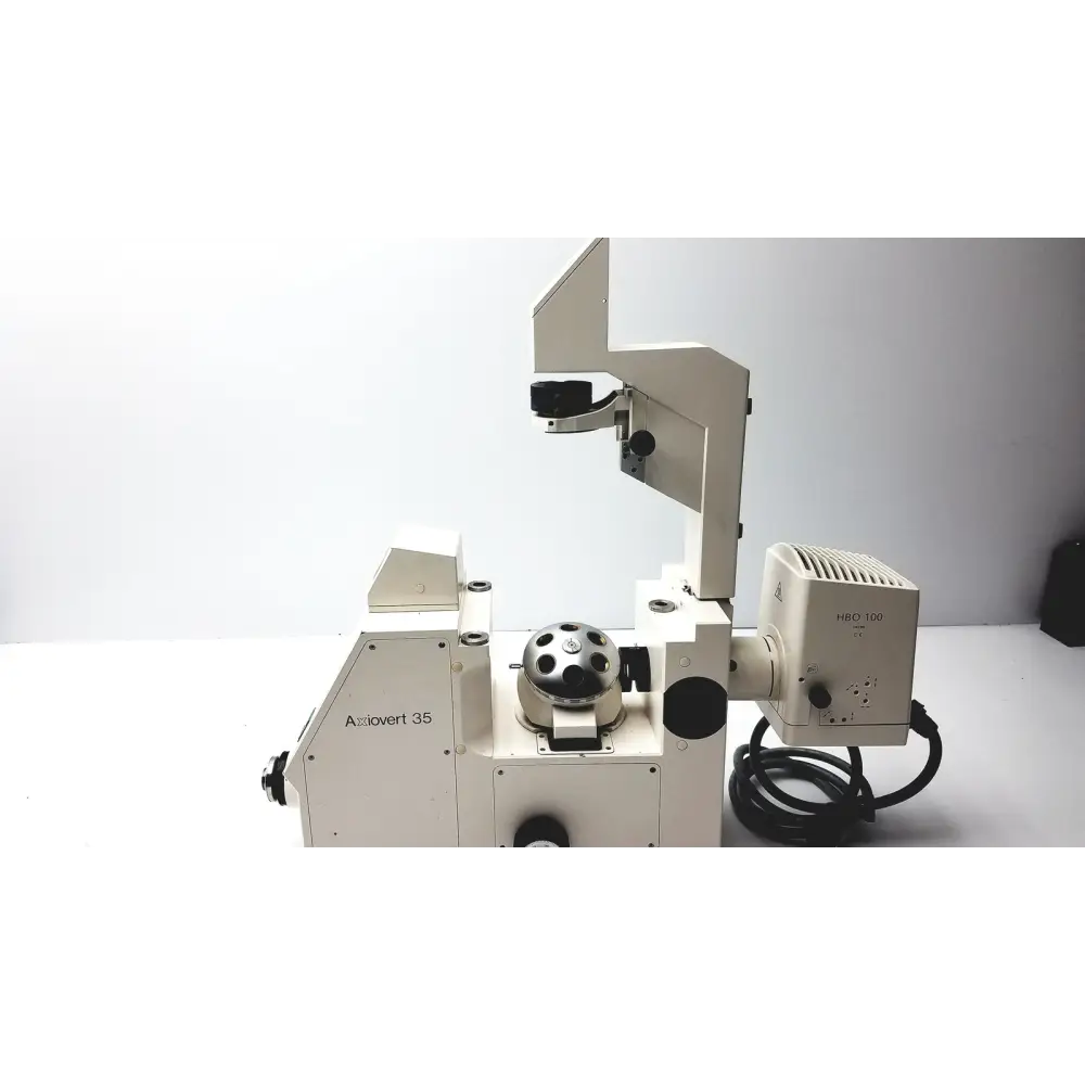 White metal microscope with black circular stage and labeled components
