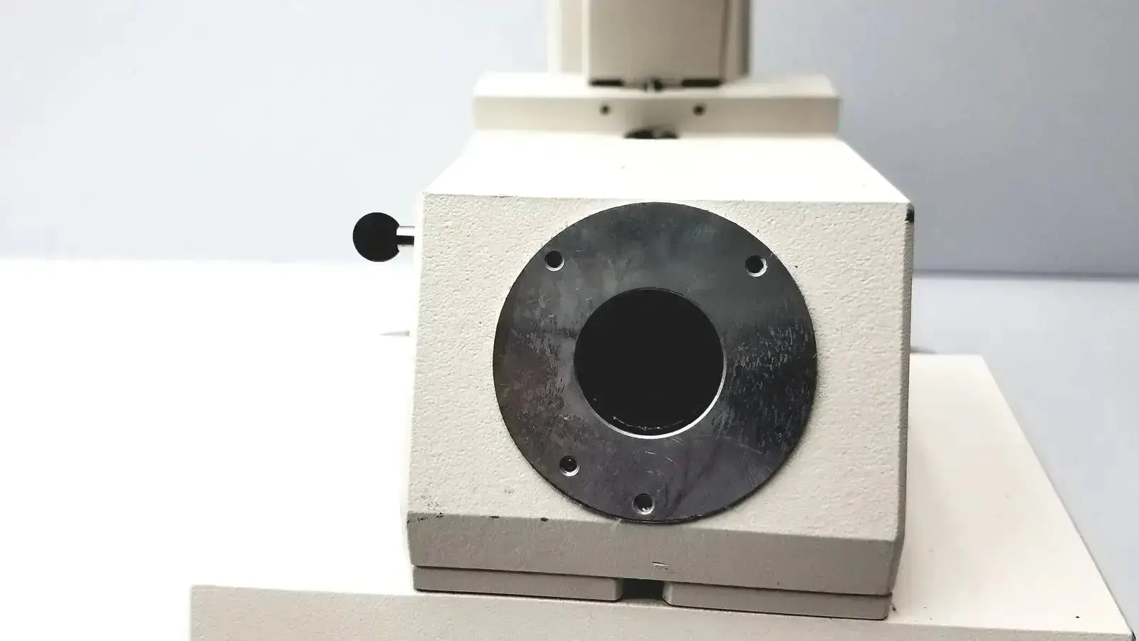 Beige-colored microscope base of axiovert 35 inverted phase contrast microscope with black metal port and knob side view