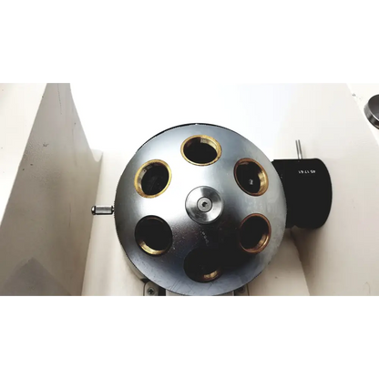 Silver metallic spherical device with six gold-ringed openings and a central screw, mounted on a white surface.