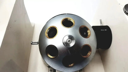 Silver metallic spherical device with six gold-ringed openings and central screw mounted on axiovert 35 inverted phase contrast microscope