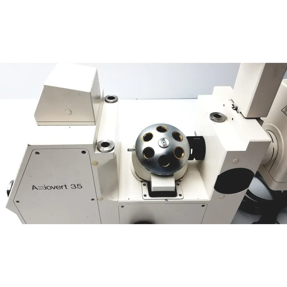 The central component is a metallic, spherical stage with multiple circular apertures and a polished chrome finish.