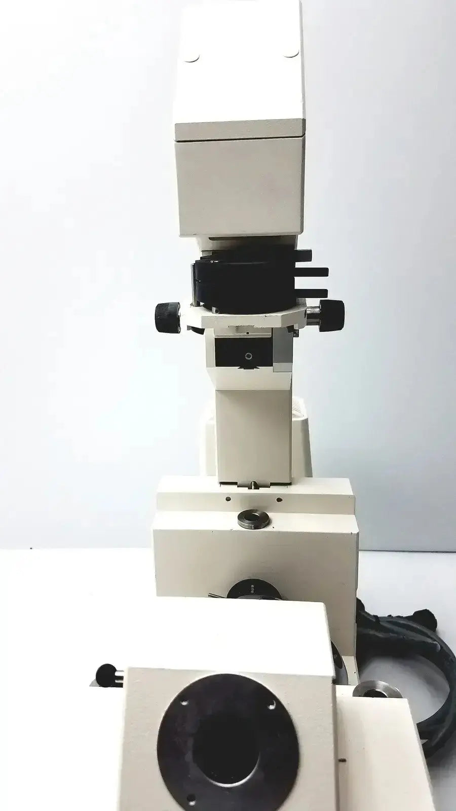 White metal Axiovert 35 inverted phase contrast microscope with black adjustment knobs and circular stage aperture