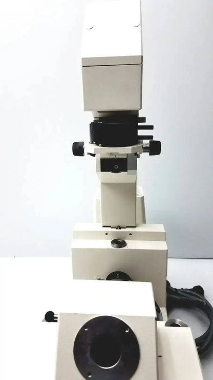 White metal Axiovert 35 inverted phase contrast microscope with black adjustment knobs and circular stage aperture