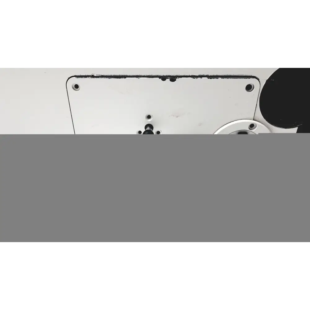 White metal plate with black screw holes and a circular component nearby