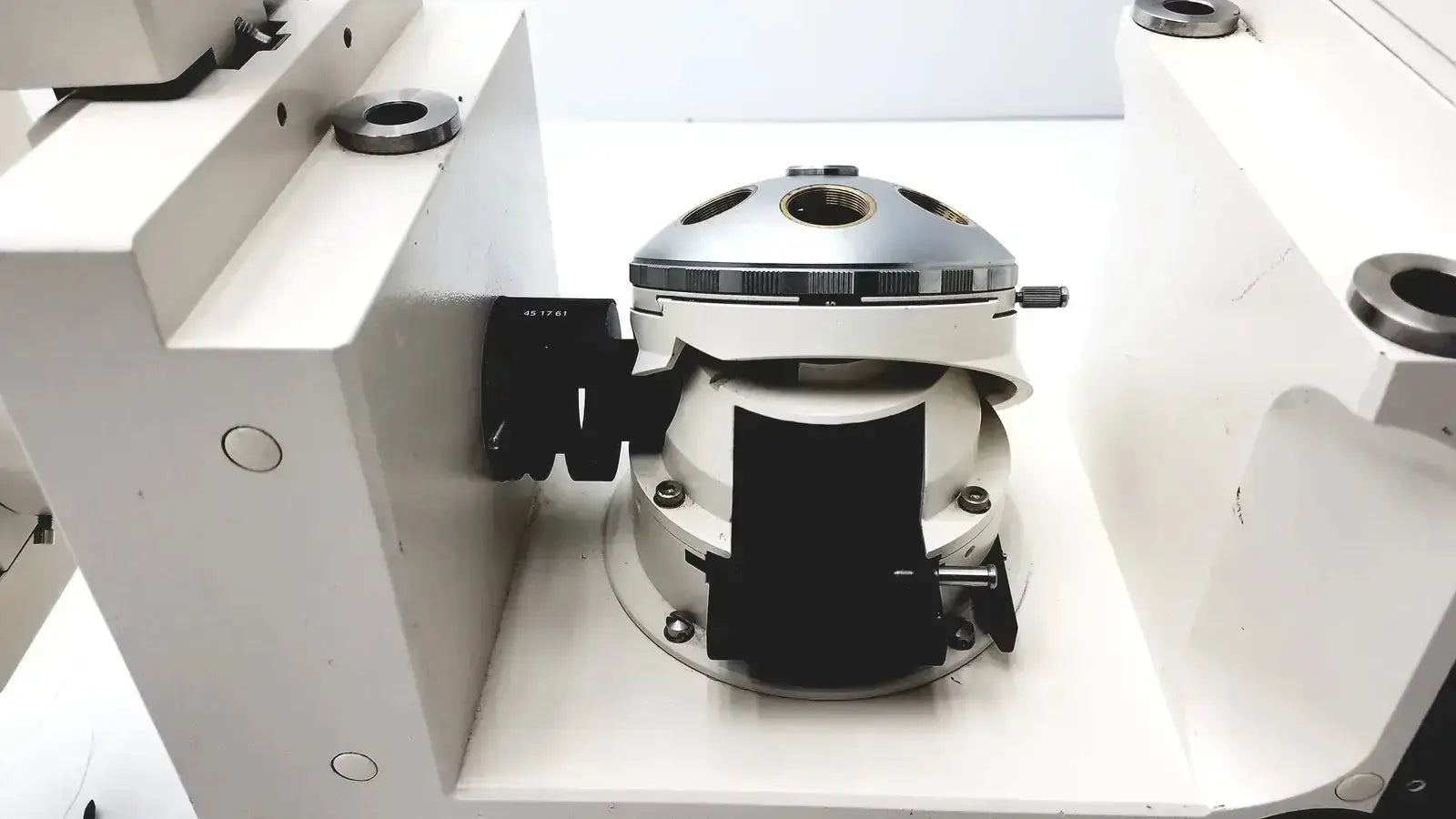 Silver and white mechanical camera lens mount with black rubberized grips on the back of axiovert 35 inverted phase contrast microscope