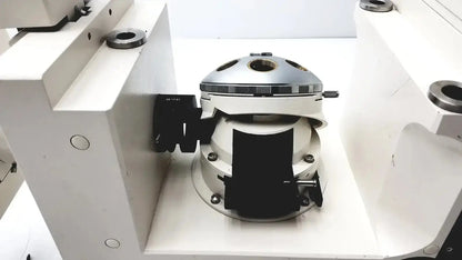 Silver and white mechanical camera lens mount with black rubberized grips on the back of axiovert 35 inverted phase contrast microscope